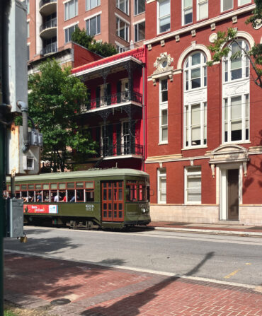 A green street car drives down a street