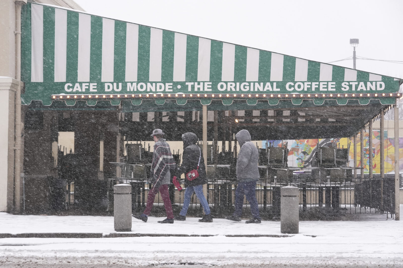 People walk by the empty Cafe Du Monde restaurant in the French Quarter in New Orleans,