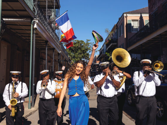 A woman in a blue suit strolls down a New Orleans street with a brass band