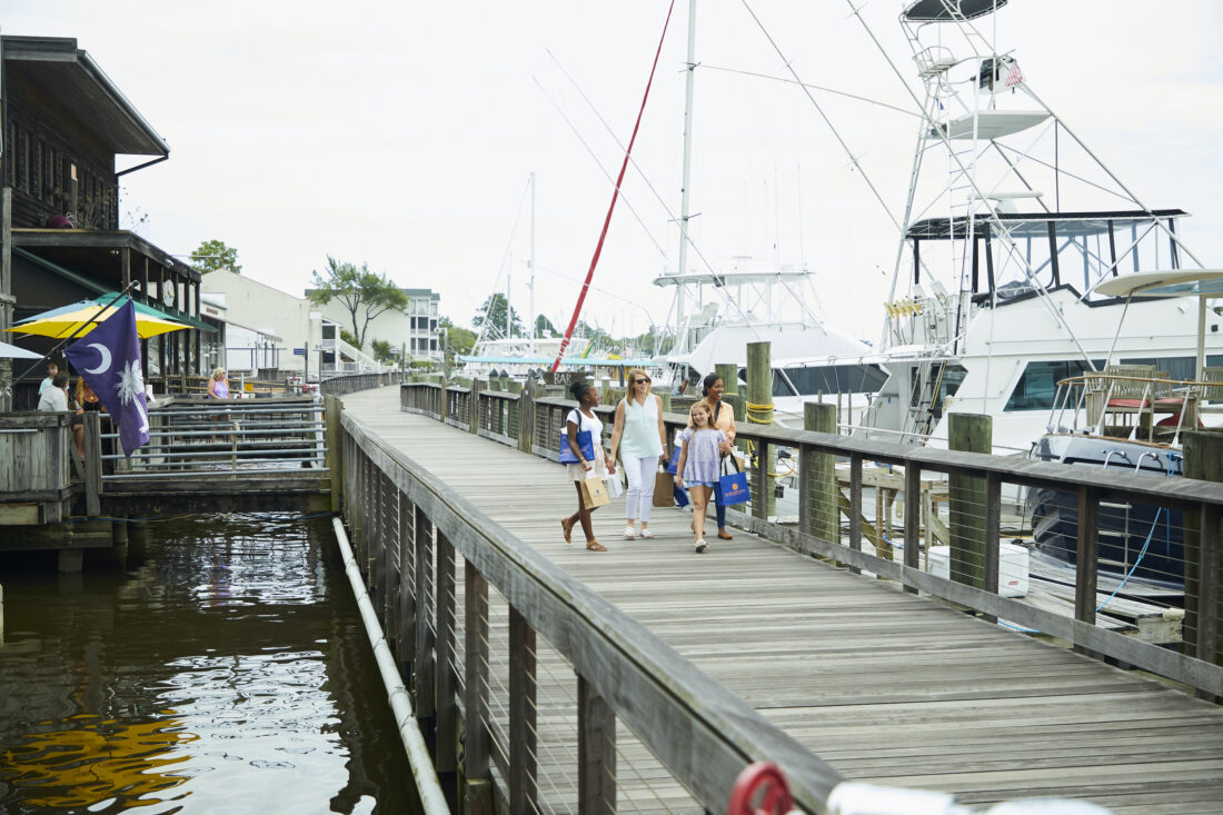 A group of women walk on a boardwalk on the water