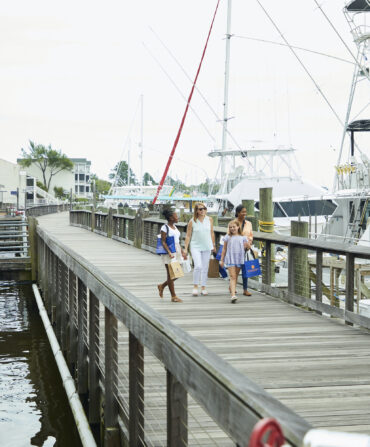 A group of women walk on a boardwalk on the water