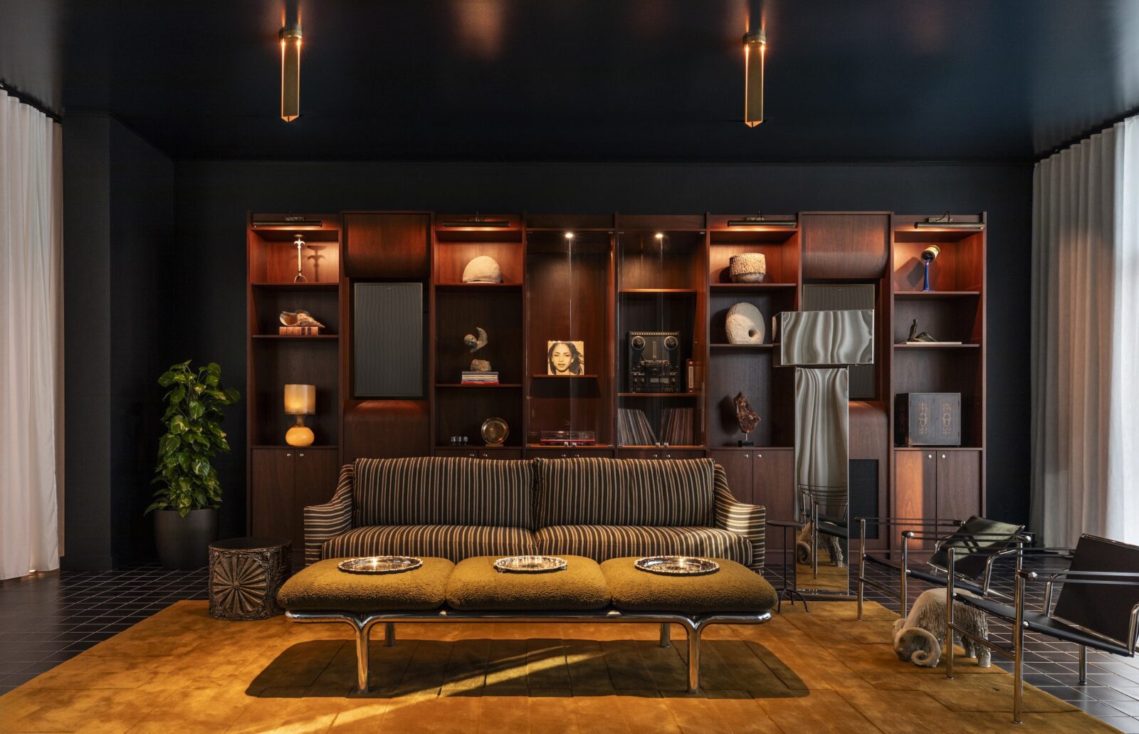 A cozy listening room with stacked shelves and a striped couch. It has black walls and yellow accents