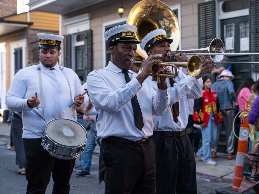 A trio of men play brass instruments in the street