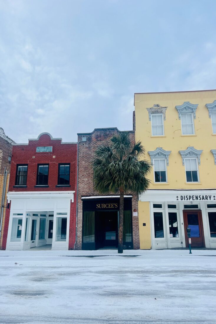A snowy street with colorful storefronts