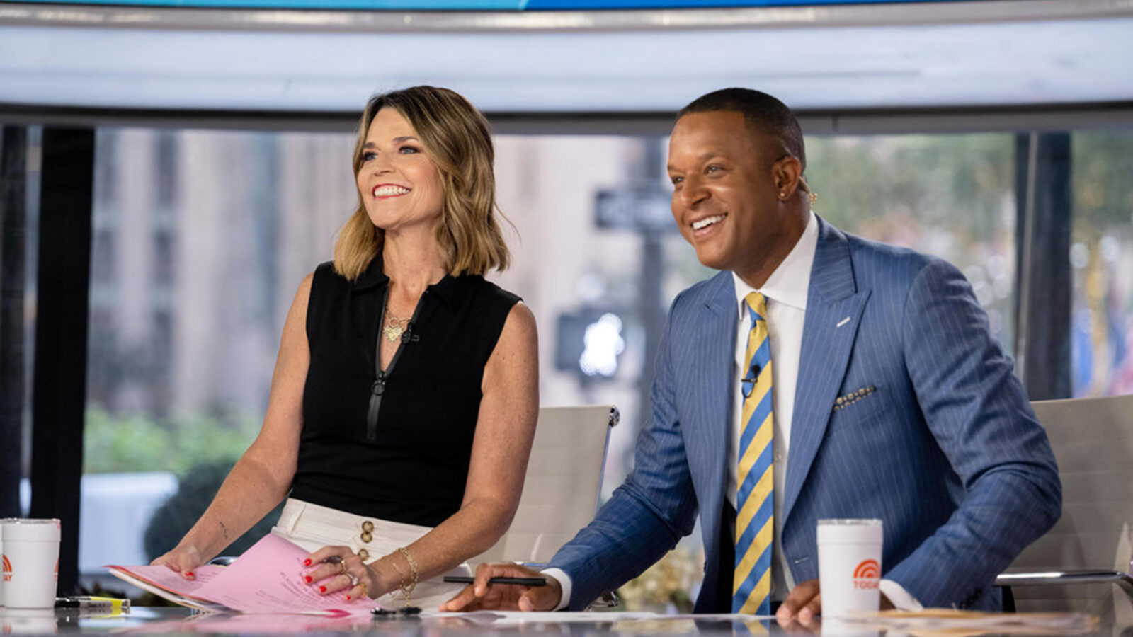 Two people sitting at a TV anchor desk