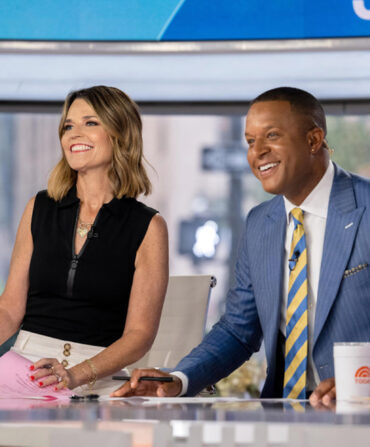 Two people sitting at a TV anchor desk