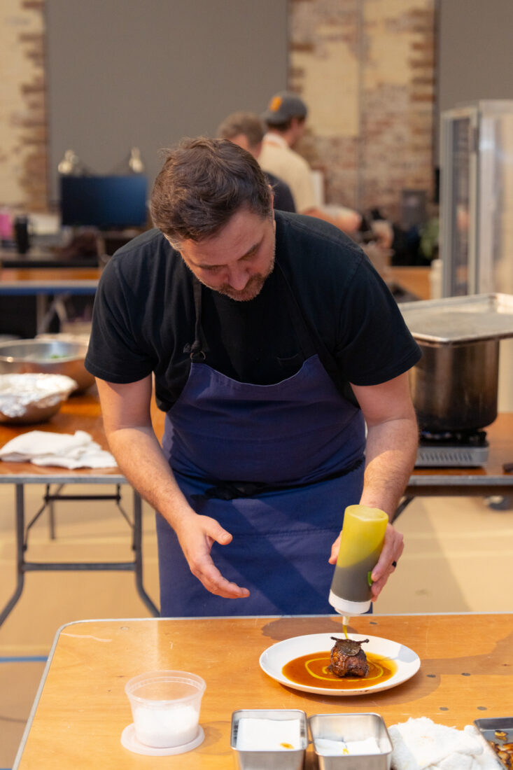Chef Daniel Heinze puts the final touches on the sky course: charcoal-grilled quail topped with winter black truffles.