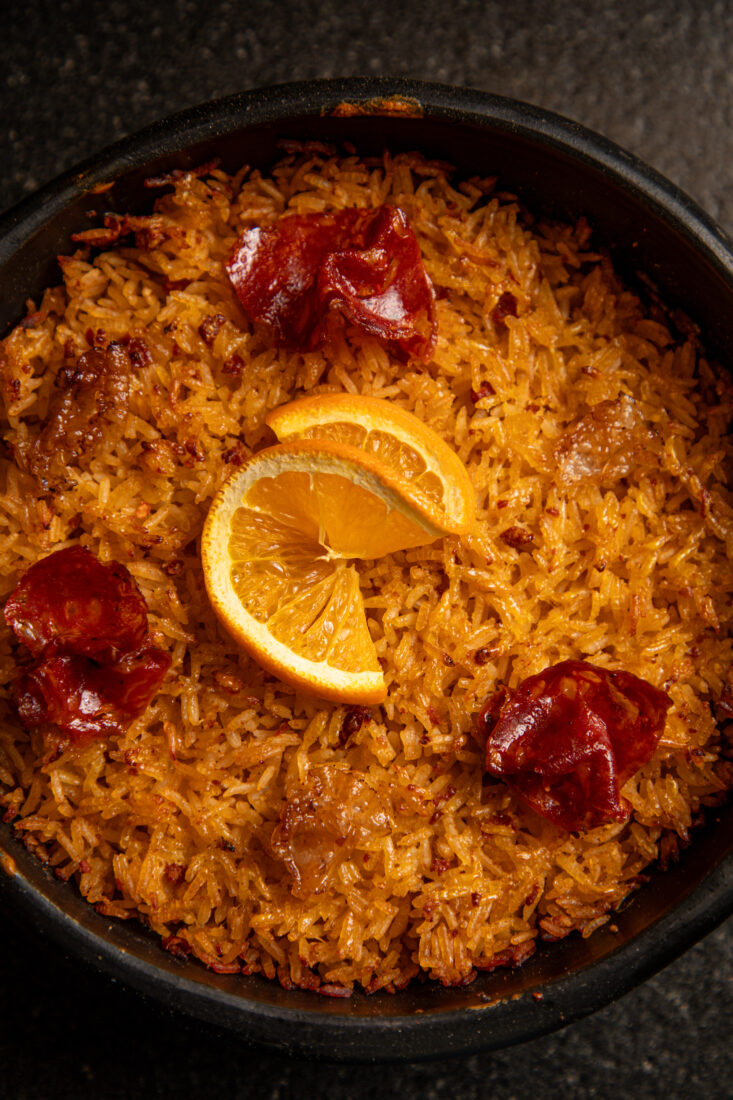 A bowl of rice with slices of duck and oranges