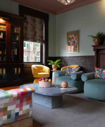 A stately living room with a brightly patterned lounge and dark wood bookcases