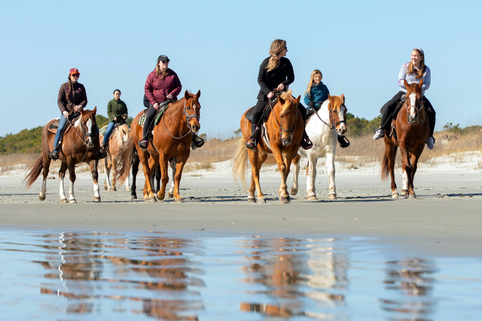 People ride horses on the beach