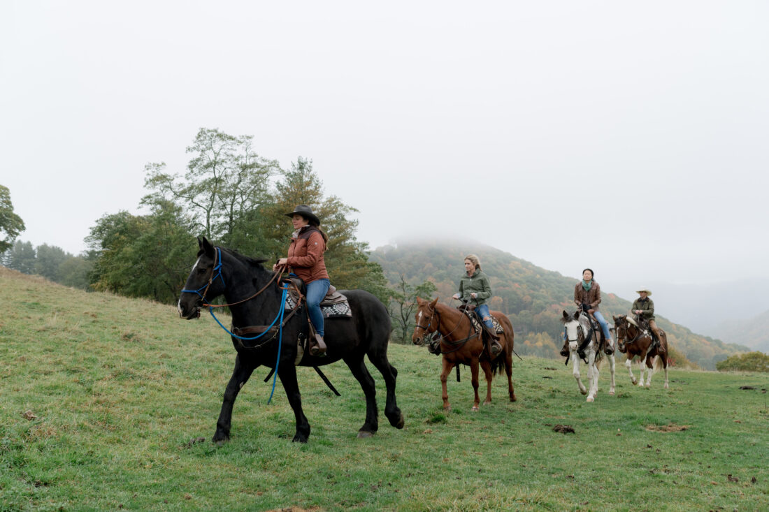 People ride horses through the mountains