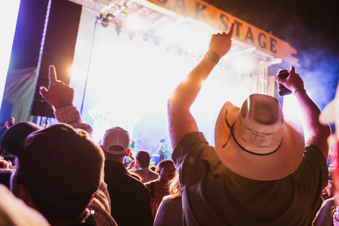 A crowd of people listen to music in front of a concert stage