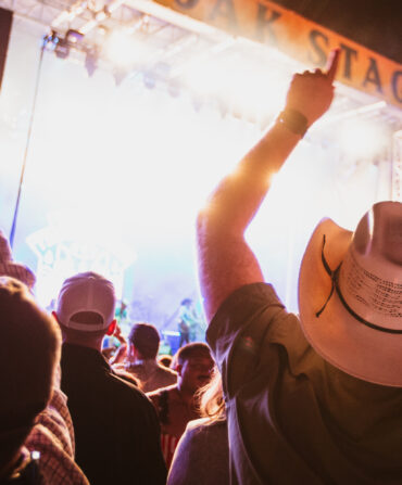 A crowd of people listen to music in front of a concert stage