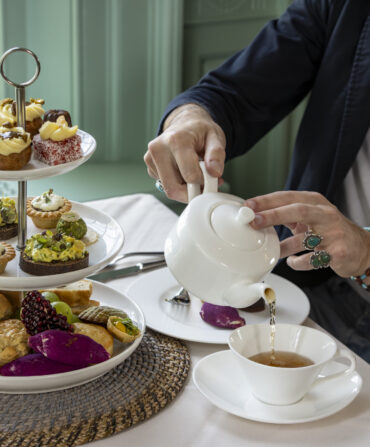 A person pours tea at a table with snacks