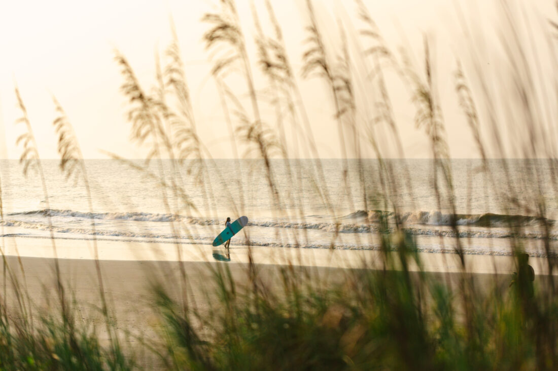A surfer heads out to the water on a beach