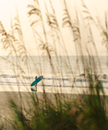 A surfer heads out to the water on a beach