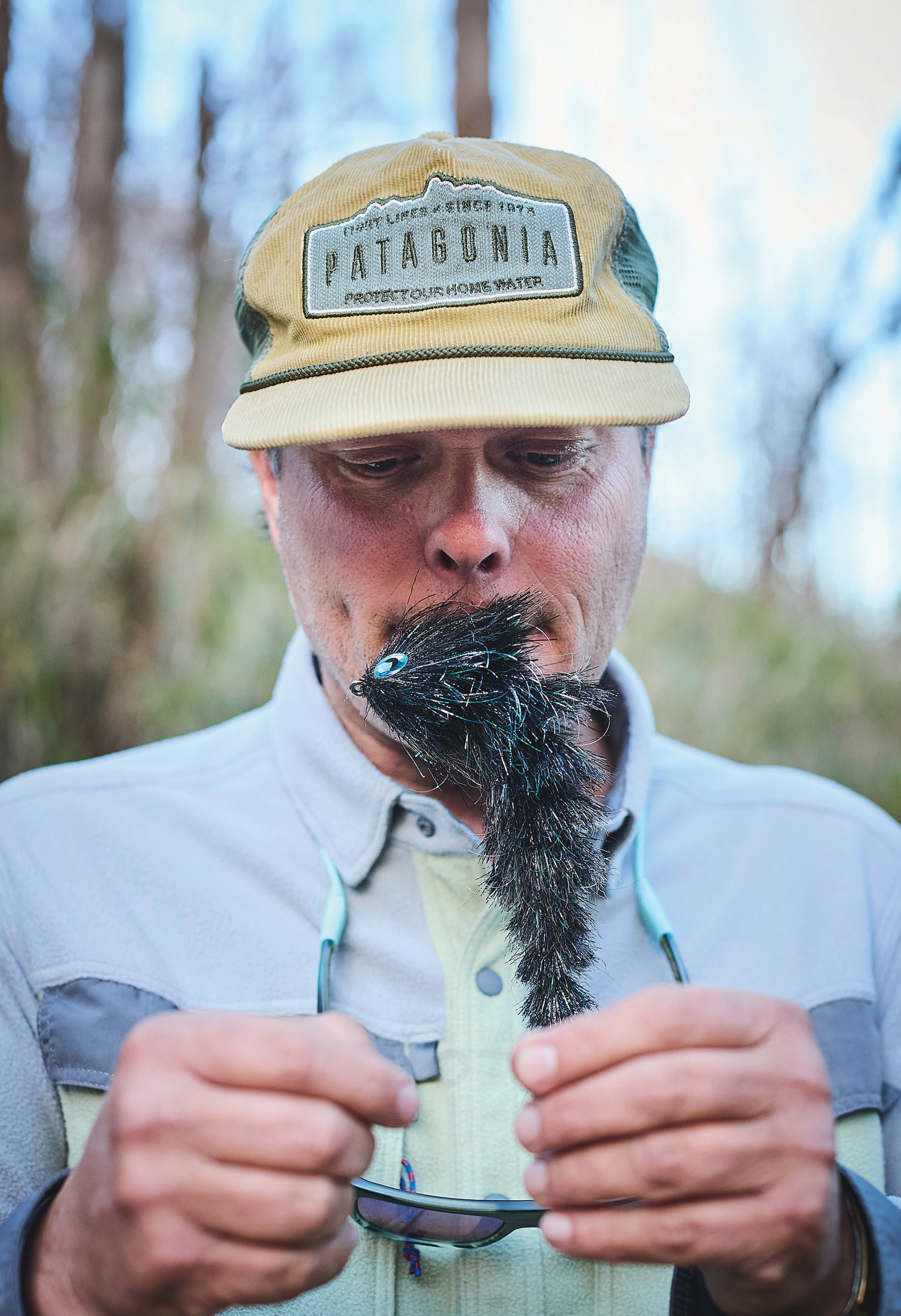 A man holds a large fly hook in his mouth