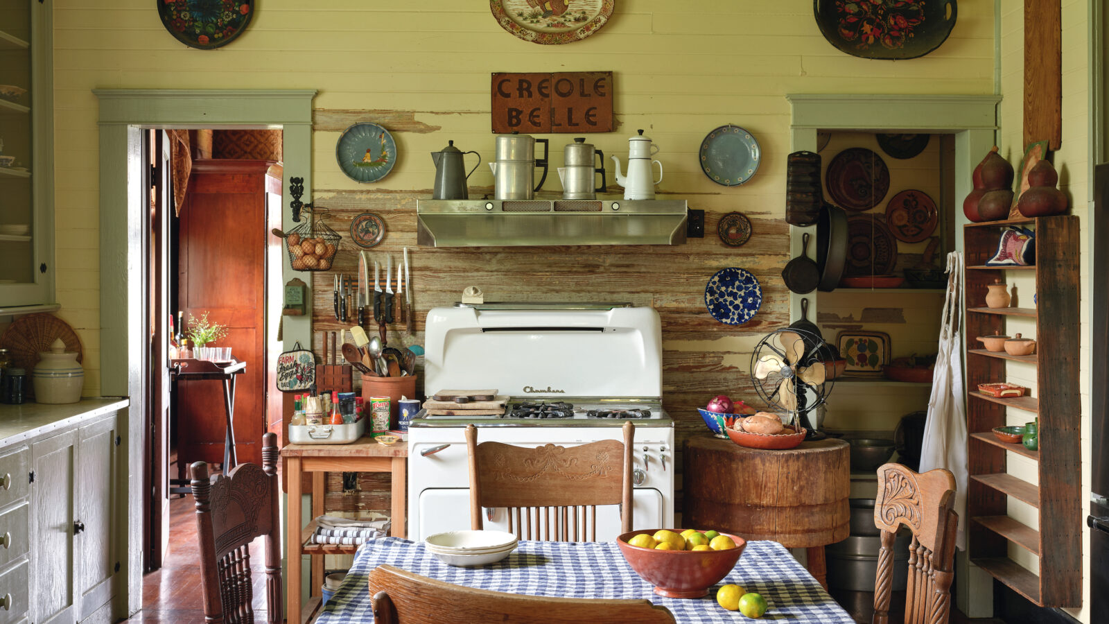 Antique percolators, mismatched dishware, and worn cutting boards adorn the cozy kitchen.