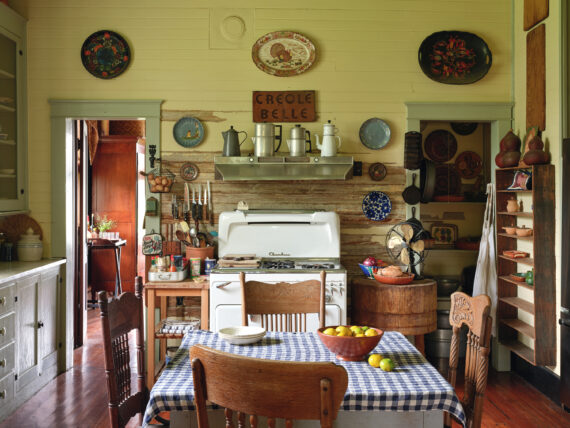 Antique percolators, mismatched dishware, and worn cutting boards adorn the cozy kitchen.