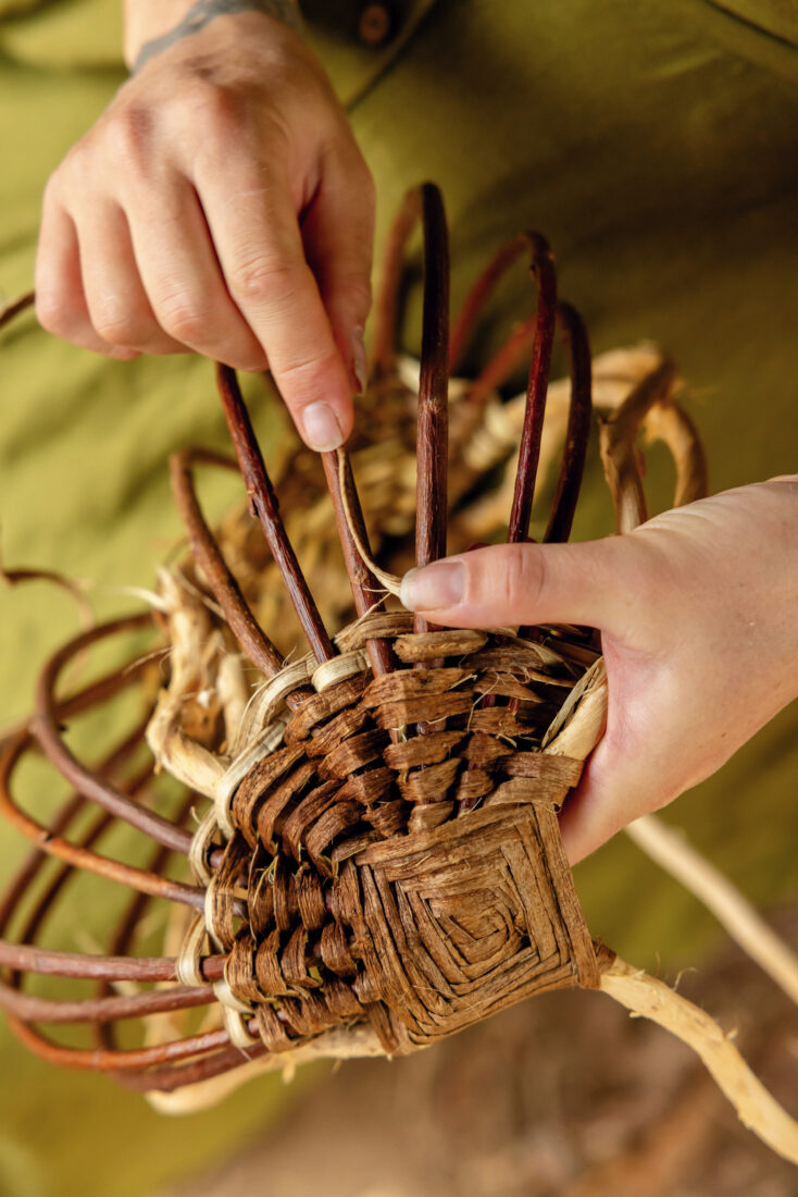 Hands weave a basket