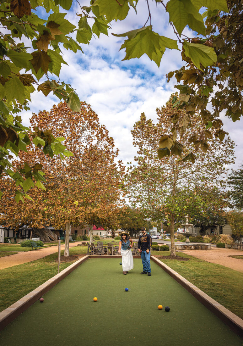 People play bocce ball outside in a park