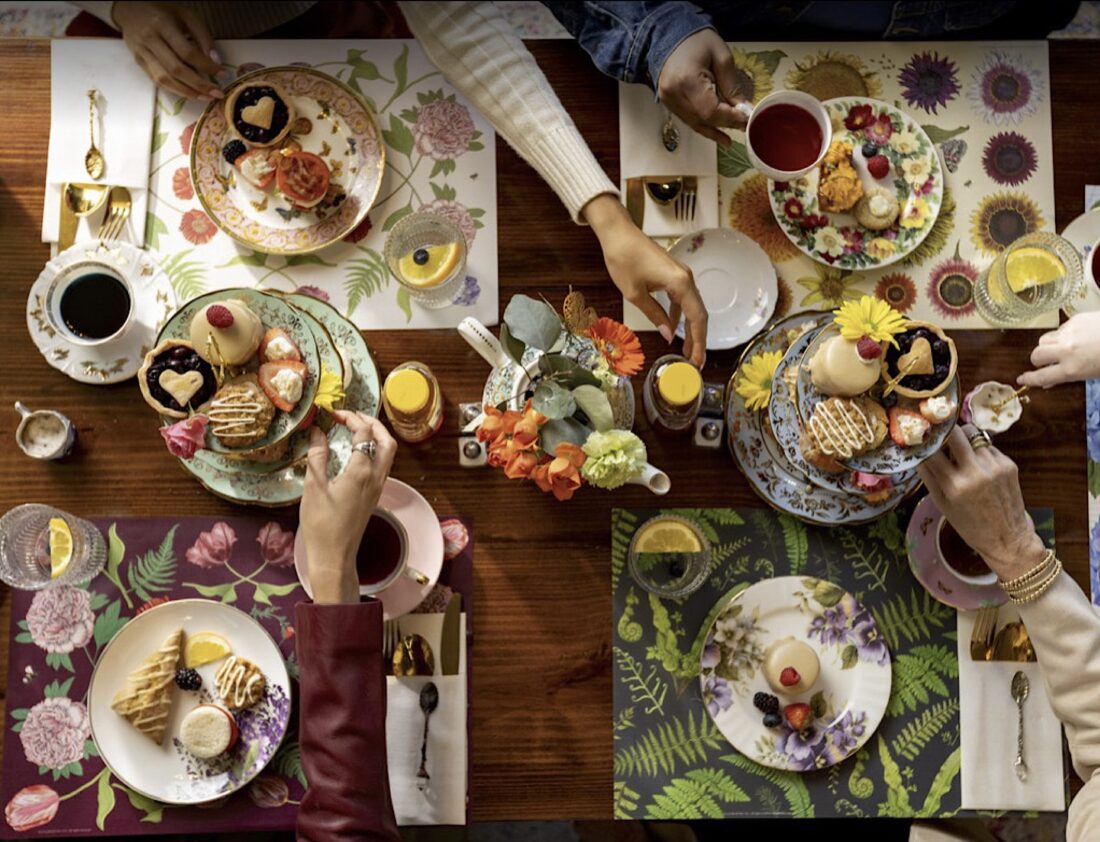 A spread of tea snacks and tea on a table with floral settings