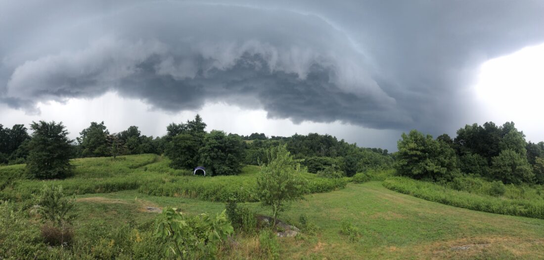 A rolling landscape of green hills with storm clouds