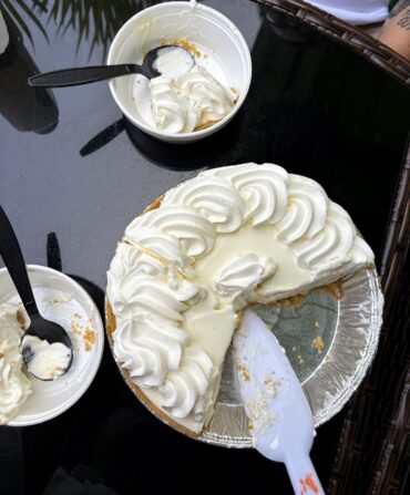 A key lime pie, sliced with plastic bowls around it