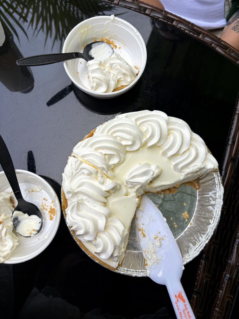 A key lime pie, sliced with plastic bowls around it