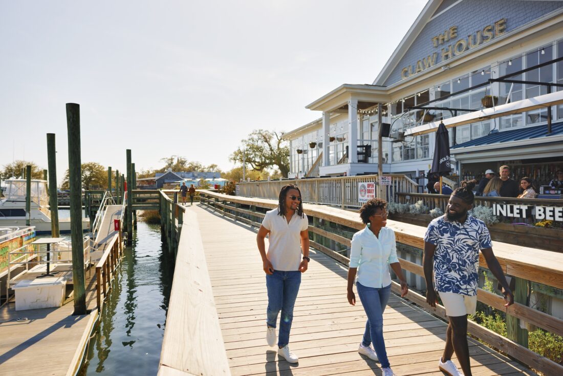 People stroll down a dock by the water
