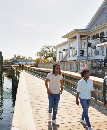 People stroll down a dock by the water