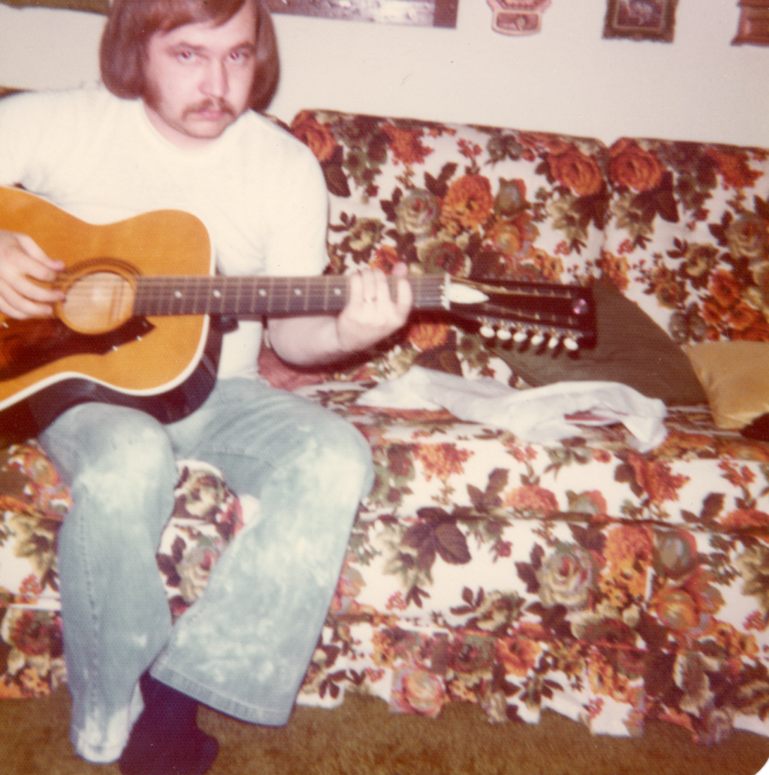 An old photo of a man holding a guitar