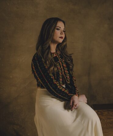 A portrait of a woman sitting against a brown background