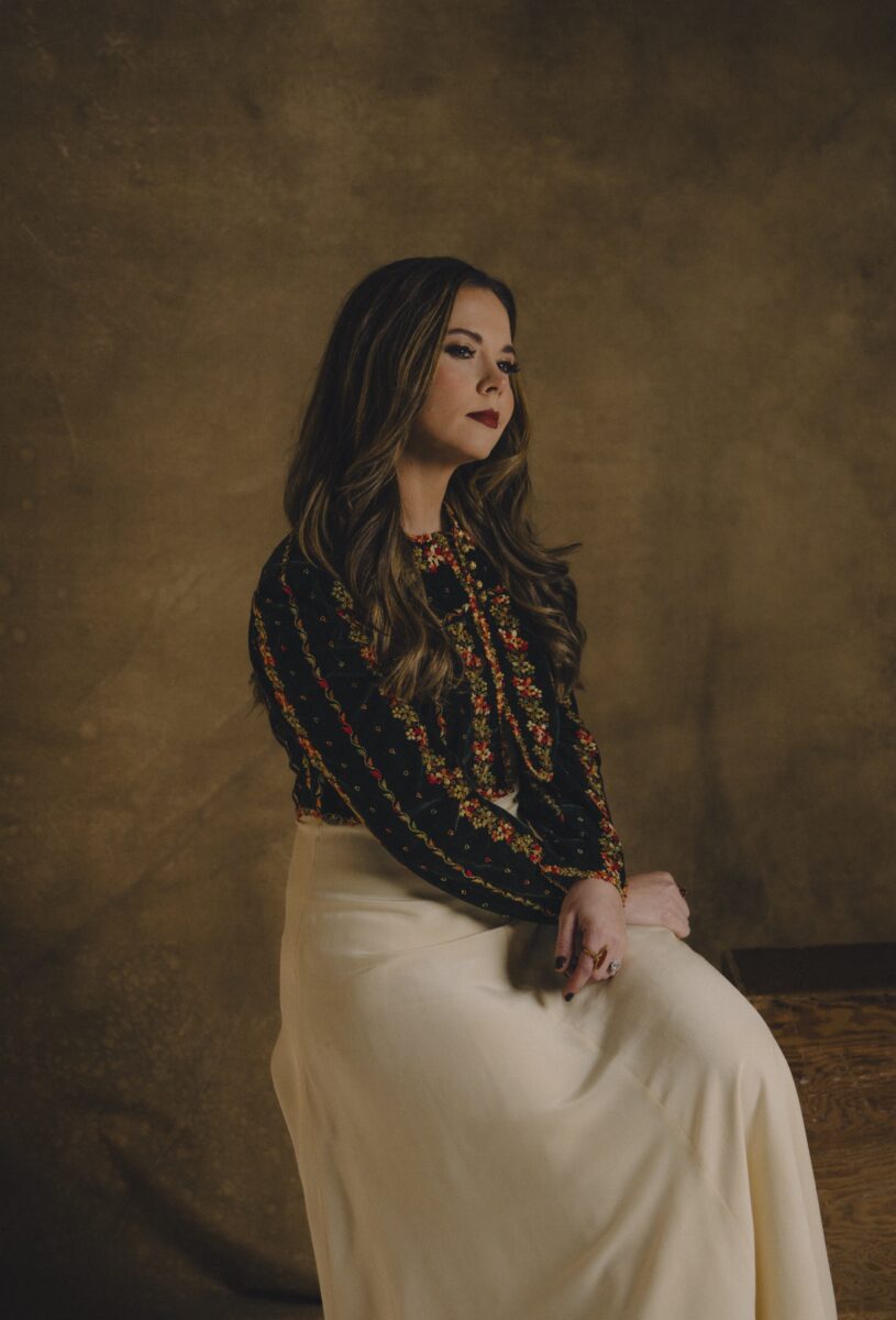 A portrait of a woman sitting against a brown background