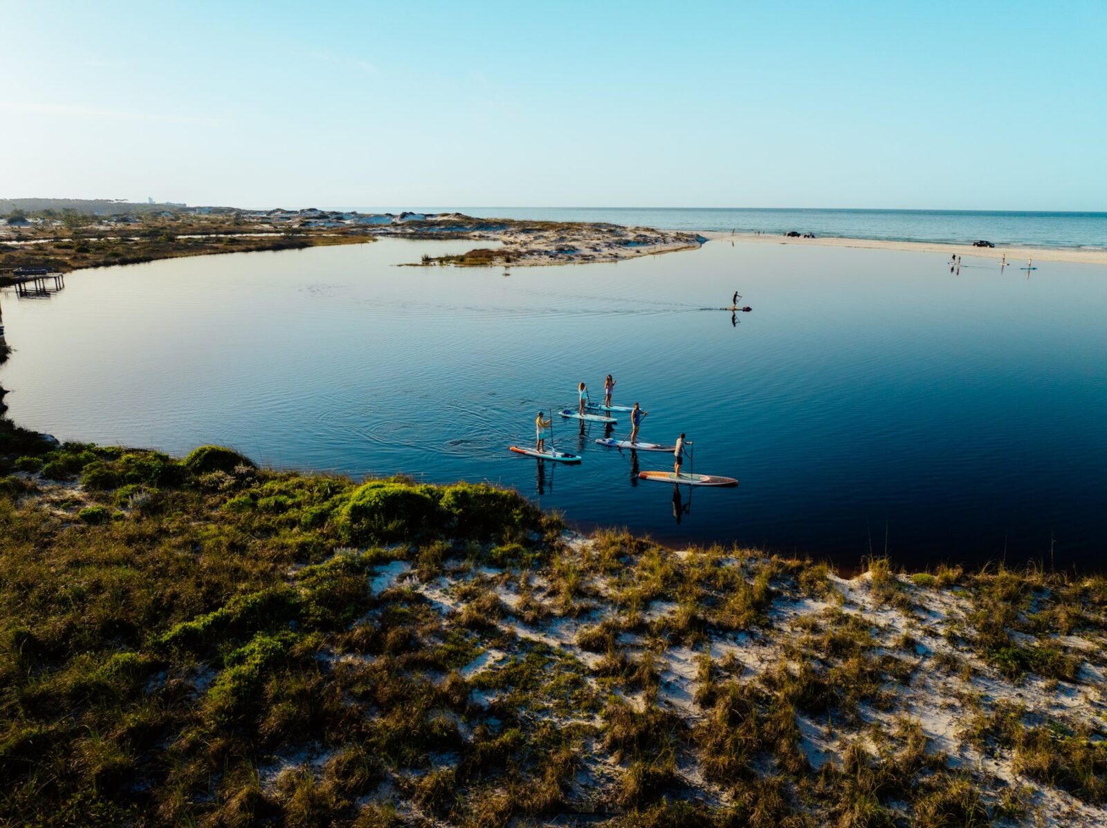 A group of people paddle board on a beach