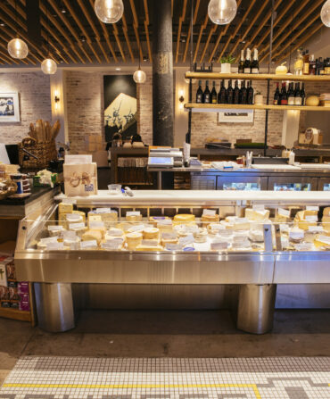 Inside a cheese shop with a case of cheese and tiled floors