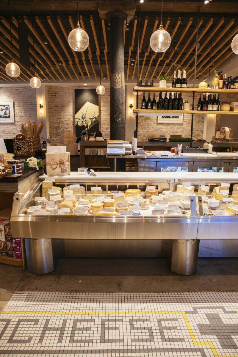 Inside a cheese shop with a case of cheese and tiled floors