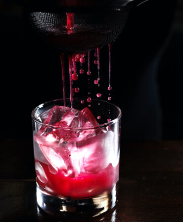 Red juice strains into a cocktail glass