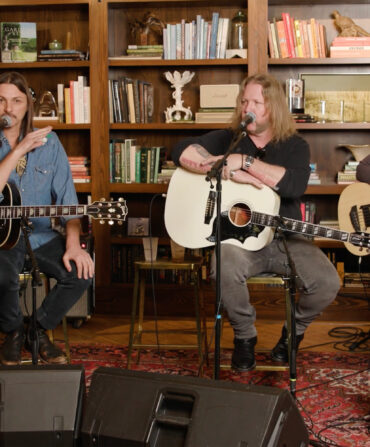 Four guitarists sitting on a small stage