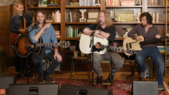 Four guitarists sitting on a small stage