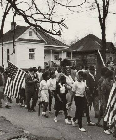 Civil rights activists march and carry American flags