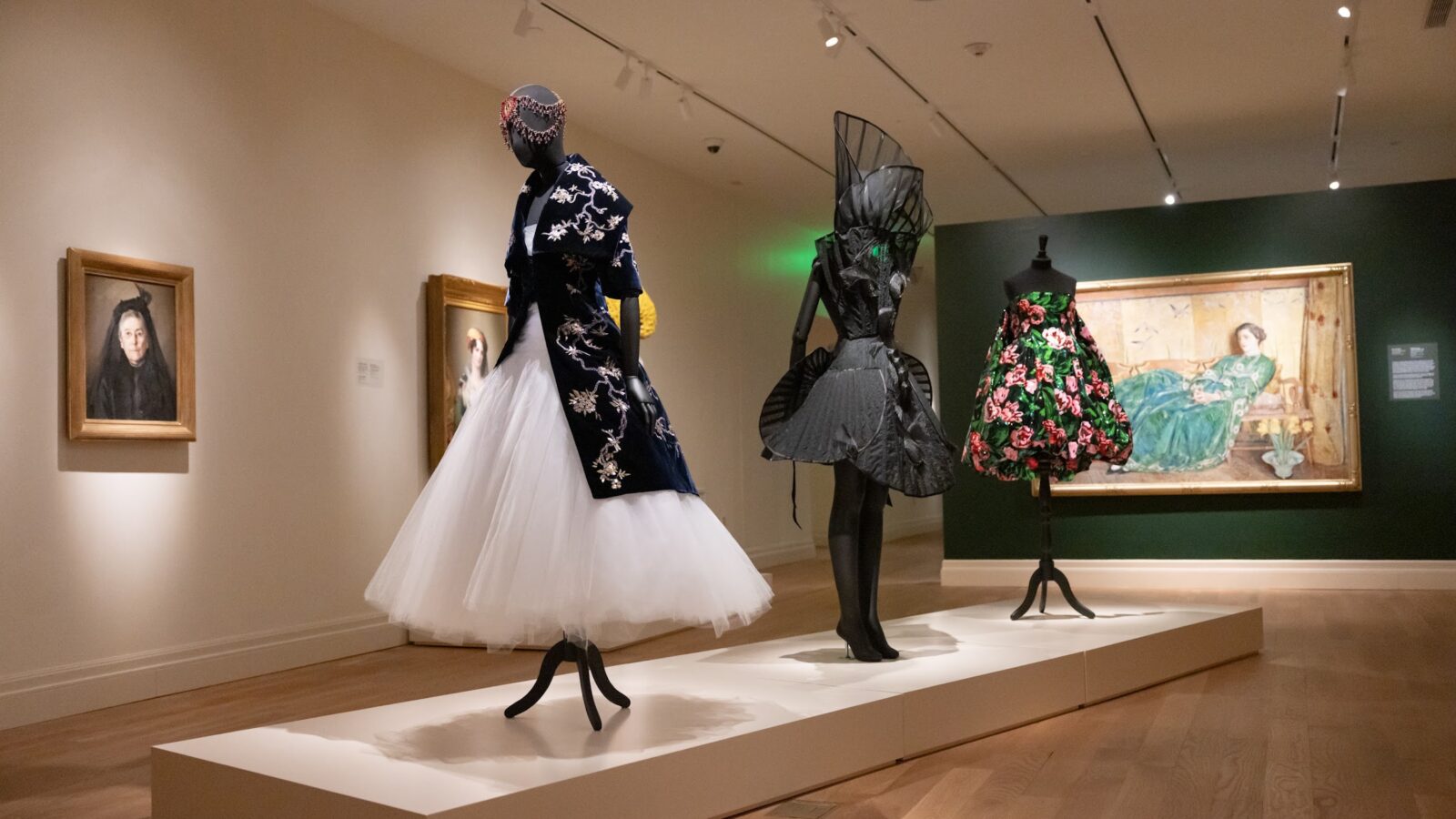 A display of a museum exhibit with stunning high fashion designs paired with paintings