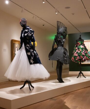 A display of a museum exhibit with stunning high fashion designs paired with paintings