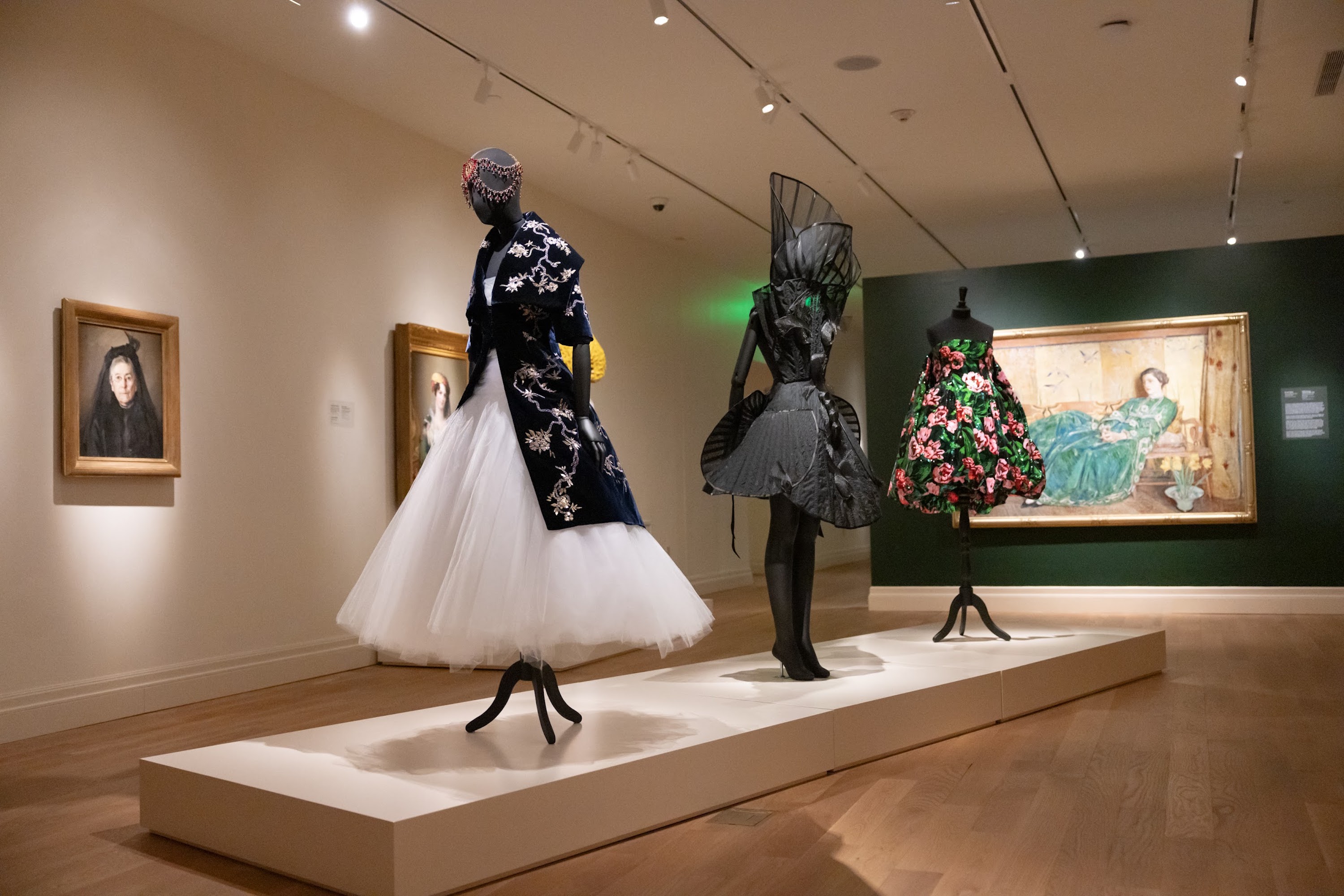 A display of a museum exhibit with stunning high fashion designs paired with paintings