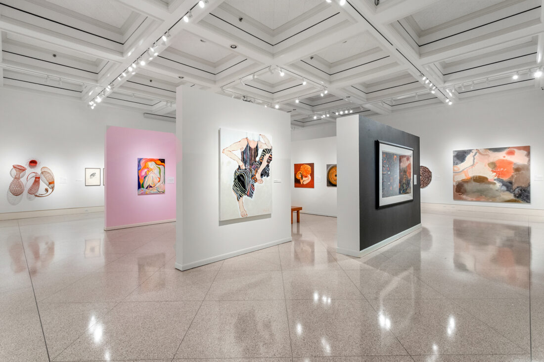A white art gallery with paintings on the wall