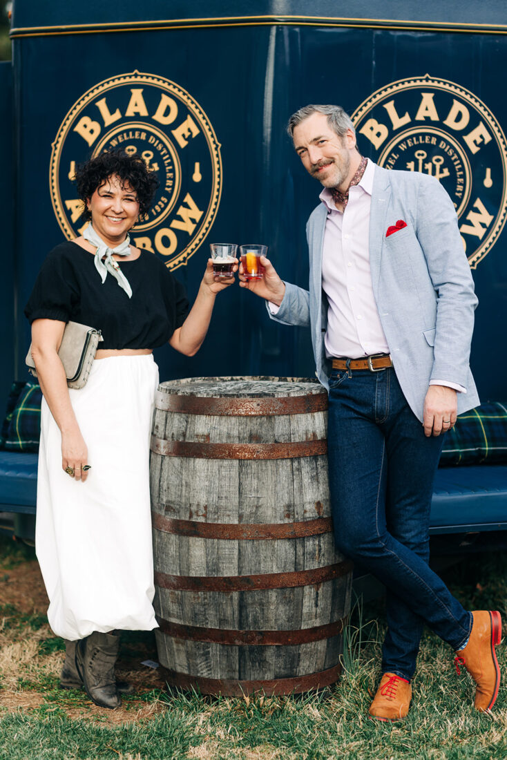 Millita Gonzalez and Chall Gray toast in front of the Blade and Bow horse trailer bar.
