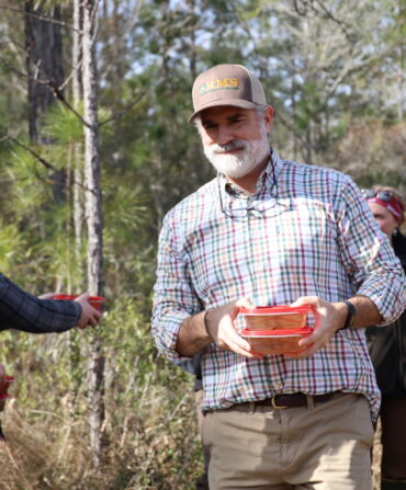 A man walks through the woods with two plastic containers