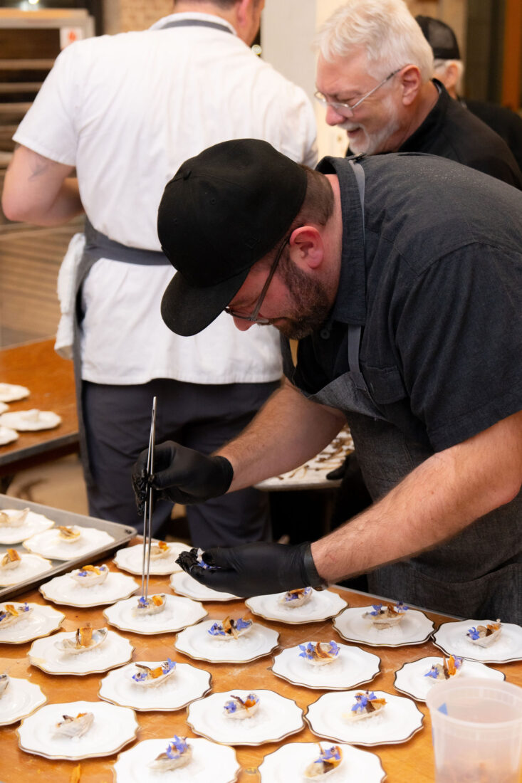 Chef Andrew McCabe puts finishing touches on the first course: butter-poached oyster: oyster root, oyster mushroom, and oyster leaf.