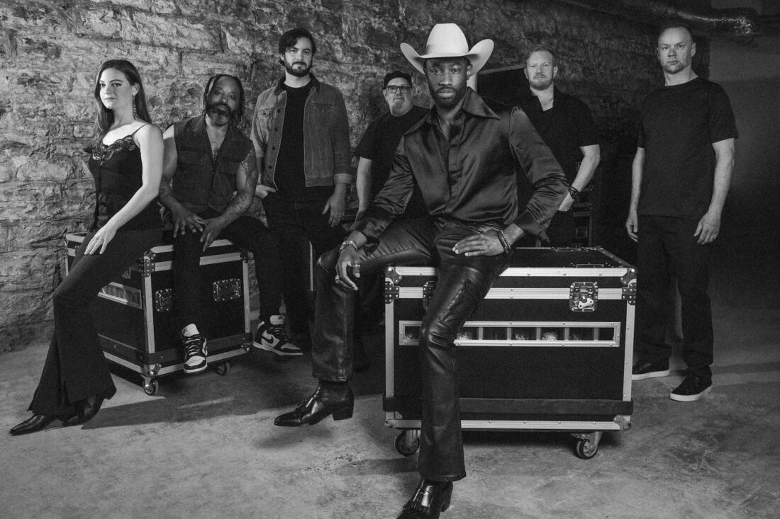 A group of people in a band pose on storage containers for instruments