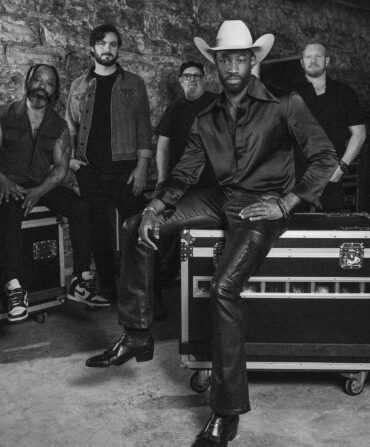 A group of people in a band pose on storage containers for instruments